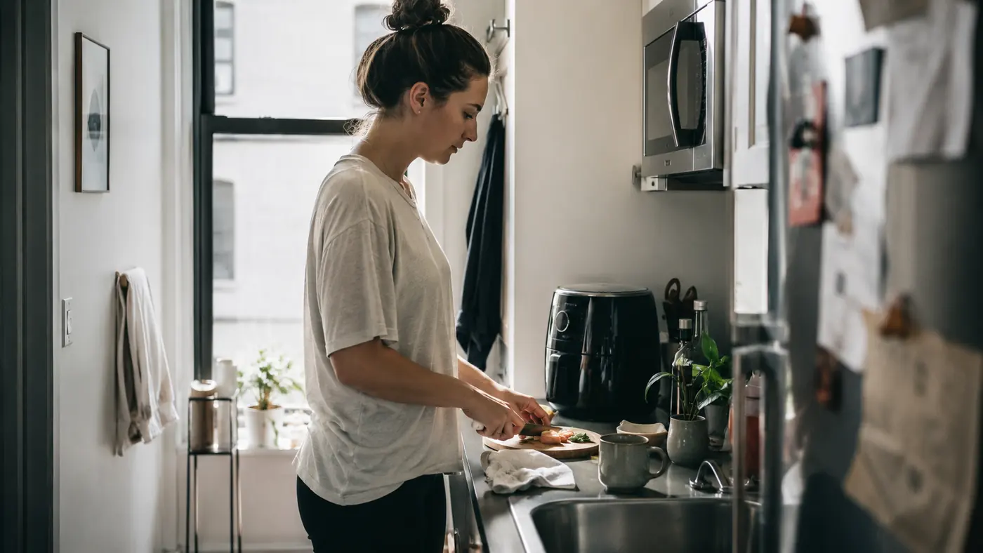 Narrow apartment galley kitchen with about three feet of counter space and a compact air fryer near the sink