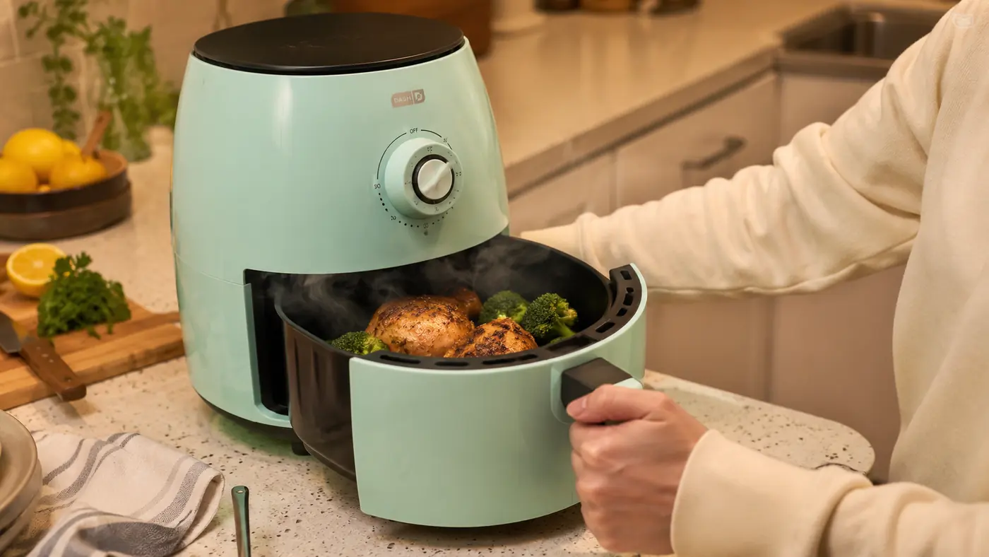 Close-up of roasted broccoli and chicken thighs coming out of the Dash Tasti-Crisp basket on a weeknight