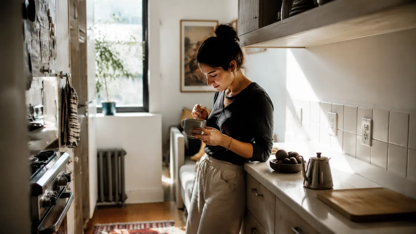 A narrow galley apartment kitchen counter with two outlets and about three feet of usable space, soft morning light through a small window